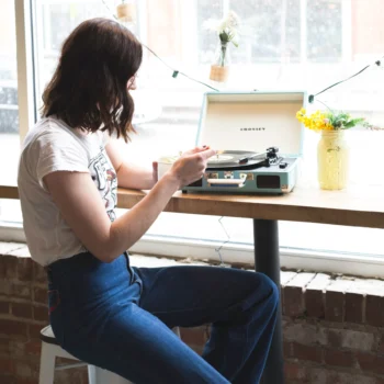 Girl playing a vinyl album on Crosley Cruiser Bluetooth Portable Record Player in Turquoise colour.